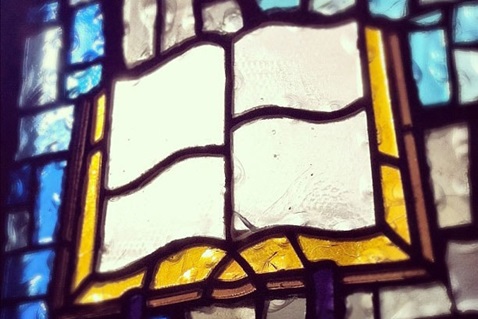 Photo of a stained glass window that shows the Bible. We believe that the Bible is the primary authority for our faith and practice.