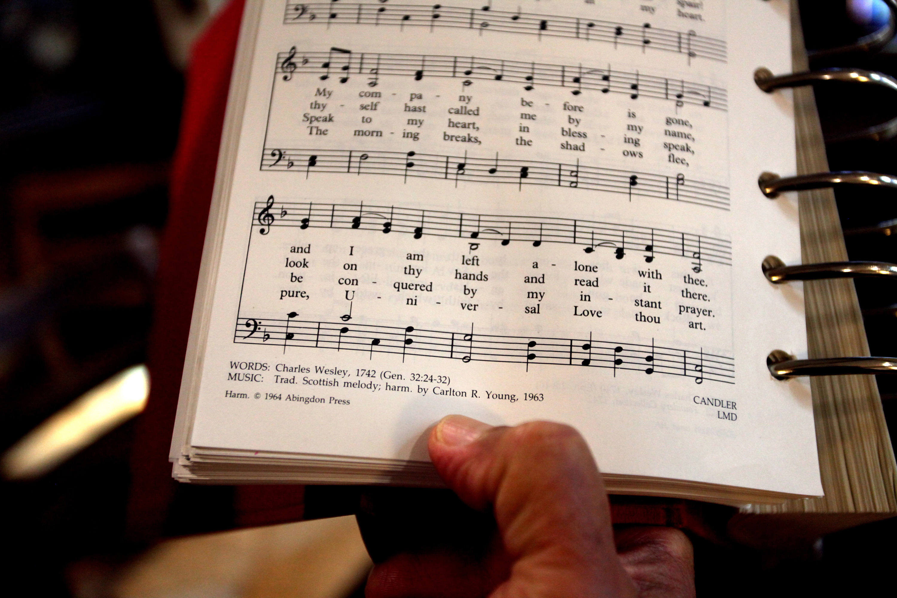 The Rev. Romero del Rosario holds a songbook featuring the lyrics written by Charles Wesley in 1742, "Come, O Thou Traveler Unknown." Photo by Kathleen Barry, UM News.