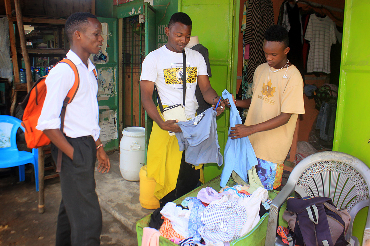 Peter Rua (left) buys clothes at a store run by Tazama Youth in Christ in Mombasa County, Kenya. The program, a ministry of Tazama Christ United Methodist Church, provides training and employment opportunities at secondhand clothing stores, car washes, refreshment kiosks and other business ventures. Photo by Gad Maiga, UM News.
