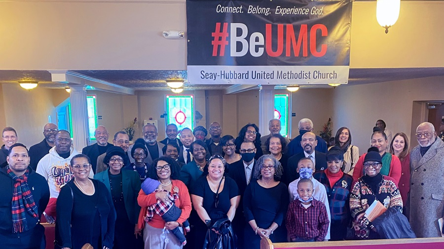 Members of Seay-Hubbard United Methodist Church pose in front of their #BeUMC sign.