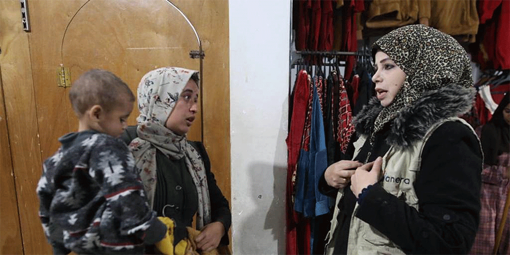 ANERA staff member assists a woman looking for winter clothes and a coat for her son. (Photo: Courtesy of ANERA)
