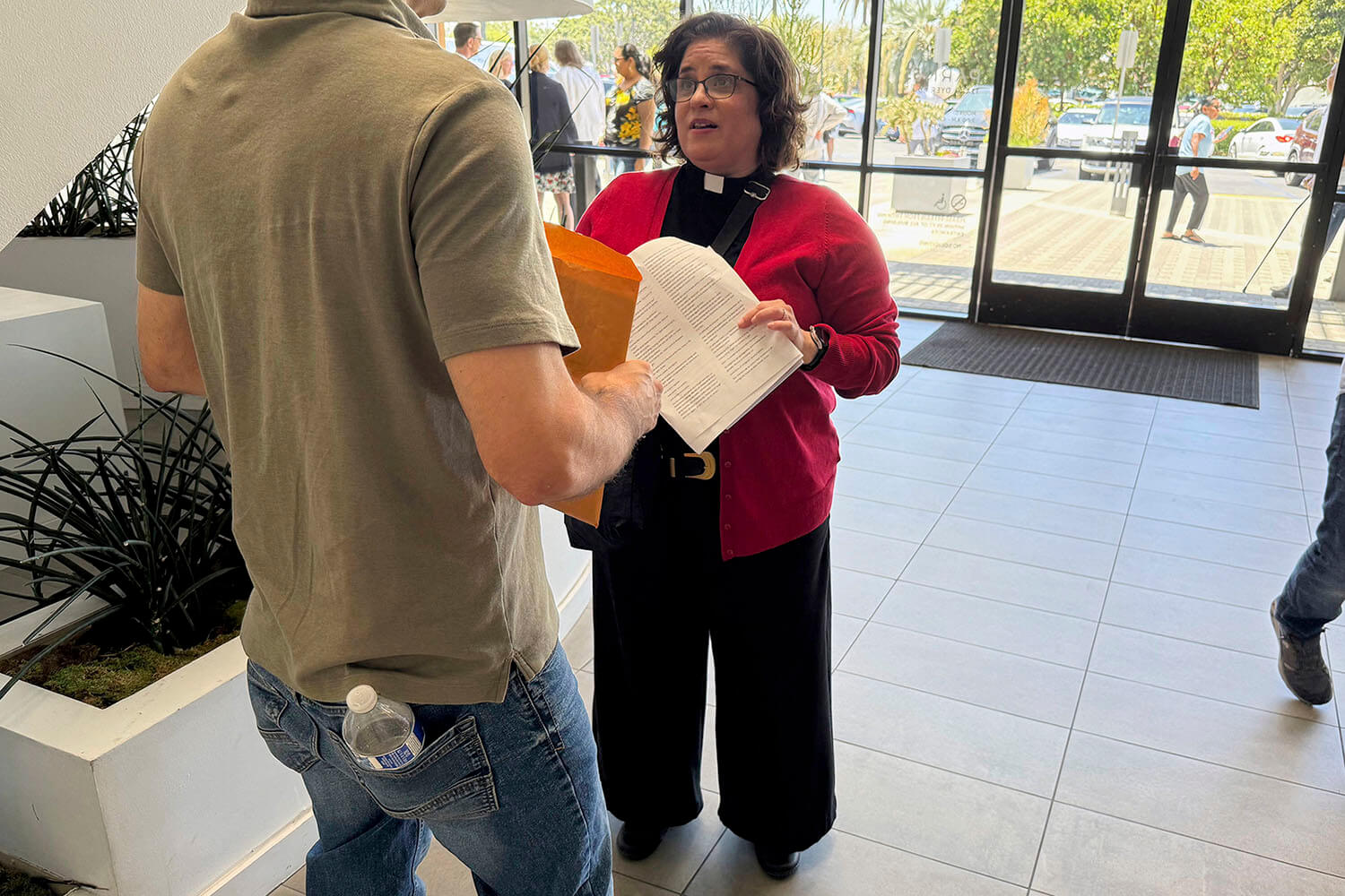 A Revda. Oona Casanova Vazquez, pastora principal da Igreja do Nazareno de South Bay, em Torrance, conversa com um homem que ela está prestes a acompanhar a uma audiência no Tribunal de Imigração de Santa Ana, em Santa Ana, Califórnia, na quinta-feira, 31 de julho de 2025. Foto Deepa Bharath , AP.